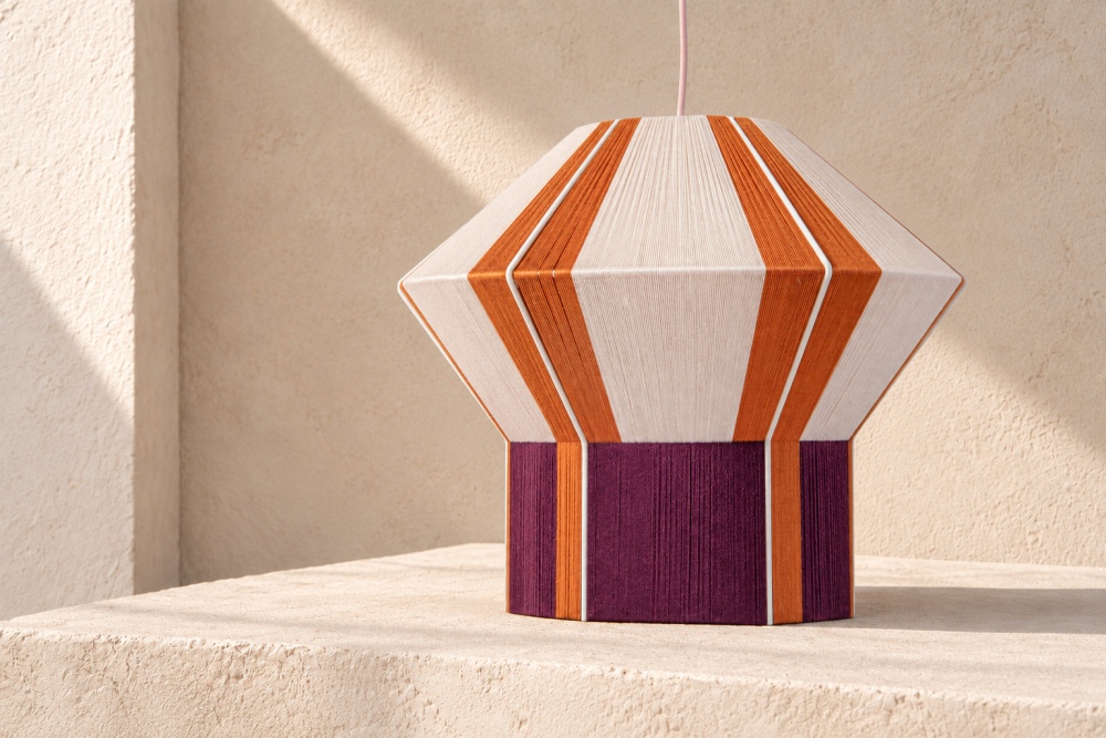 ASTYPALAIA hand-threaded pendant lamp by HOMMETRY resting on a pale stone surface