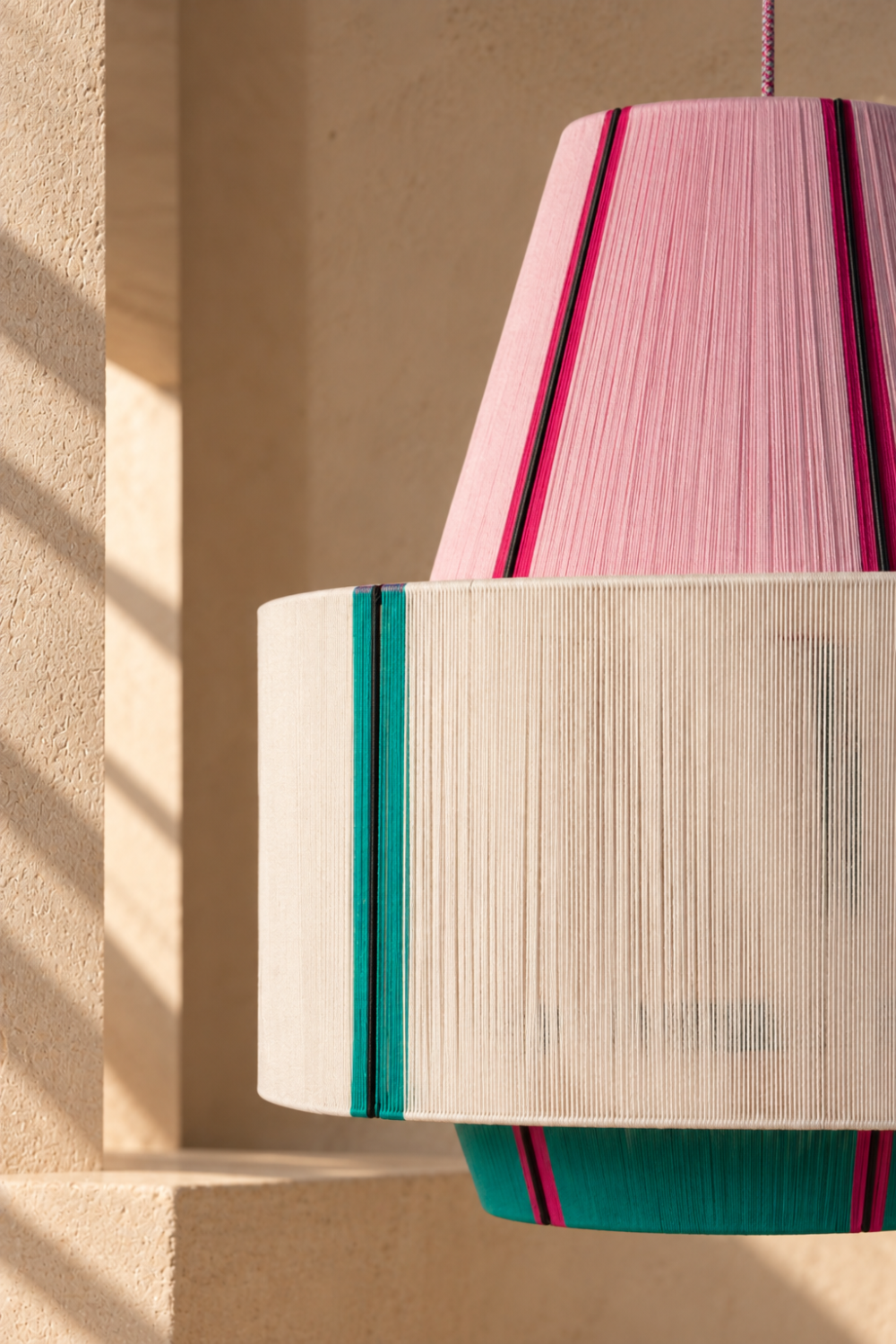 Close-up of the KARPATHOS pendant lamp showing its hand-threaded pink, cream and teal colour panels